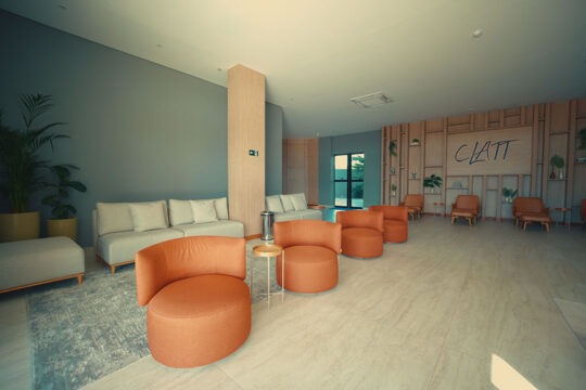 Lobby do CLATT Hotel mostrando os sofás, poltronas e painel decorativo de madeira.