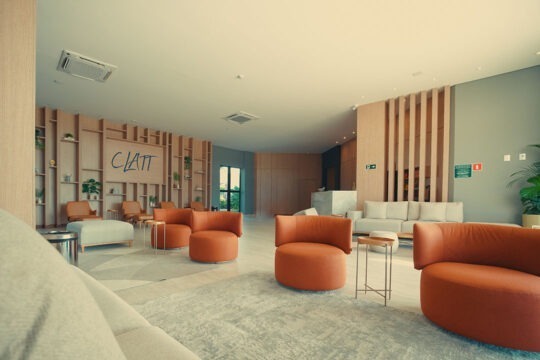Lobby do CLATT Hotel mostrando os sofás, poltronas e painel decorativo de madeira.